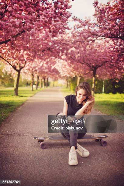 young woman with longboard in cherry blossom alley - piskunov imagens e fotografias de stock