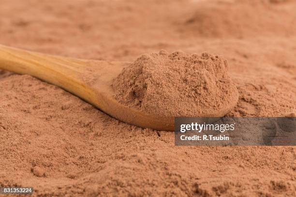 cocoa powder in wooden spoon - chocolate powder stockfoto's en -beelden