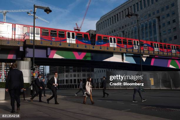 Commuters leave Heron Quay station as a Docklands Light Railway train approaches the Canary Wharf financial, business and shopping district in...