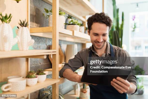 florist using digital tablet in flower shop - entrepreneur foto e immagini stock