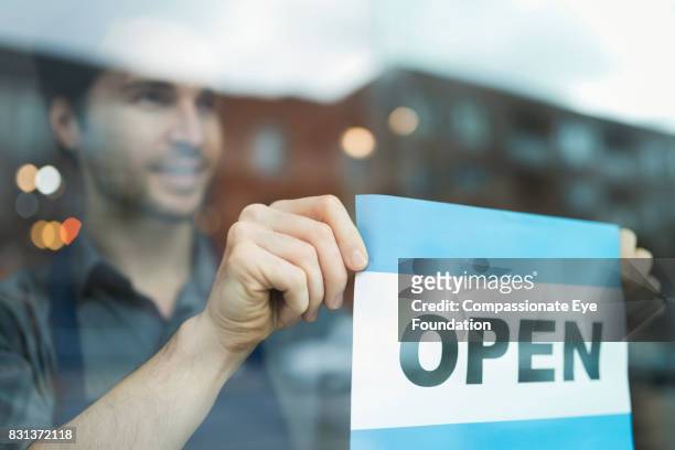 florist putting up open sign in flower shop window - cef do not delete stock pictures, royalty-free photos & images