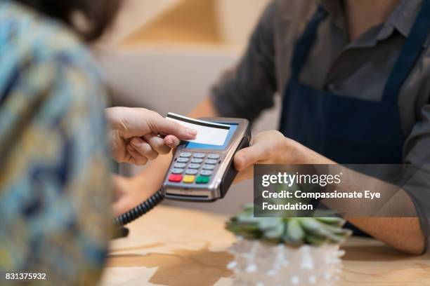 woman paying with contactless credit card in flower shop - contactless stock pictures, royalty-free photos & images