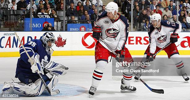 Jason Chimera and teammate Jiri Novotny of the Columbus Blue Jackets both look on as Vesa Toskala of the Toronto Maple Leafs makes a save during...