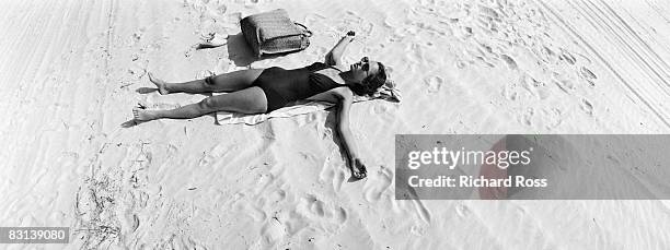 a young woman lounging on the beach - retro beach woman stock pictures, royalty-free photos & images