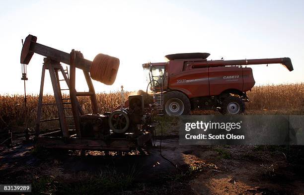 Joe Raben drives his combine past an oil well as he harvests corn on land he farms with his father and uncle October 4, 2008 near Carmi, Illinois. A...