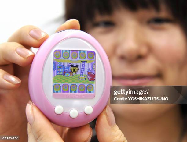 Japanese toy giant Bandai employee displays the new virtual pet toy with 1.52-inch color LCD display "Tamagotchi plus color", mega-hit egg-shaped...