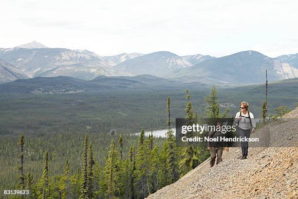 couple hiking up mountain, view below - northwest territories stock pictures, royalty-free photos & images