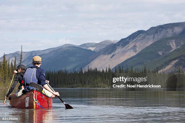 two people in canoe on calm water - northwest territories stock pictures, royalty-free photos & images