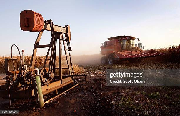 Joe Raben drives his combine past an oil well as he harvests corn on land he farms with his father and uncle on October 4, 2008 near Carmi, Illinois....