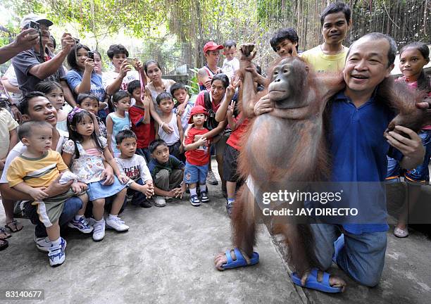 Malabon Zoo owner Manny Tangco holds a six-year-old orangutan named 'Pacquiao' in Malabon city suburban Manila as visitors looks on October 4, 2008....