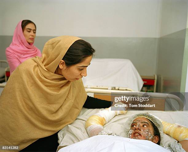 Afghani Member of Parliament Malalai Joya pictured at the bedside of a terribly burnt girl in Freedom Hospital, Kabul. Self immolation is common in...