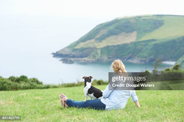 woman and jack russell terrier dog looking out to sea from coastline. - dougal waters 個照片及圖片檔