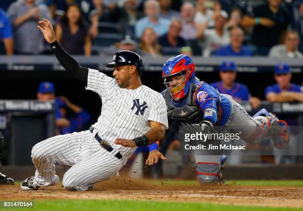 Aaron Hicks of the New York Yankees beats the tag from Rene Rivera of the New York Mets to score a run in the fourth inning at Yankee Stadium on...