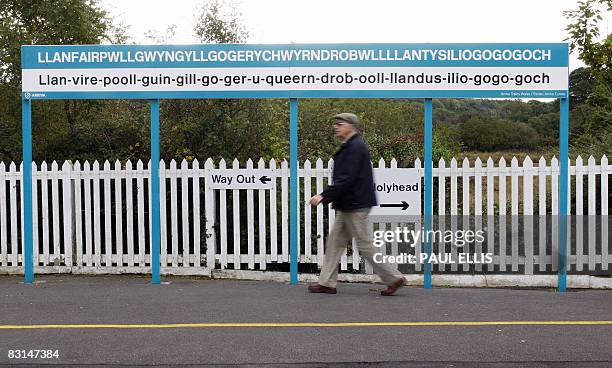 Man walks past the town sign at Llanfairpwllgwyngyllgogerychwyrndrobwllllantysiliogogogoch railway station in Anglesey, Wales, on October 6, 2008....