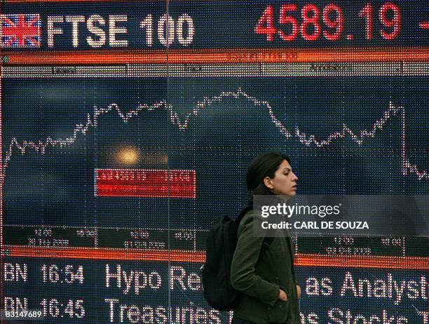 Woman walks past an electronic sign showing the progress of the FTSE 100 share index in London, on October 6, 2008. The London stock market nosedived...