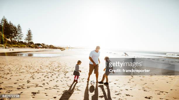 happy family playing soccer on the beach - queensland stock pictures, royalty-free photos & images