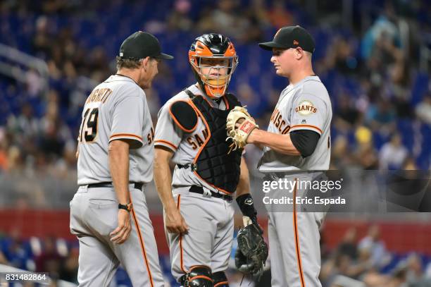 Kyle Crick of the San Francisco Giants talks with Pitching Coach Dave Righetti and Catcher Nick Hundley during the seventh inning against the Miami...