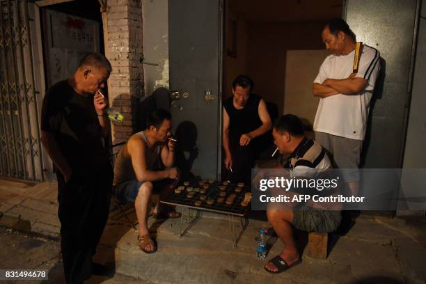 This photo taken on August 14, 2017 shows men playing Chinese chess in an alley in Beijing. The International Monetary Fund is scheduled to release...