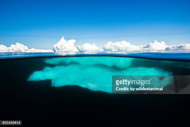 above and below the waterline view of ice formations at the ice floe edge on a bright sunny day, admiralty inlet, northern baffin island, canada. - iceberg above and below water stock pictures, royalty-free photos & images