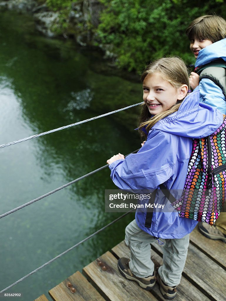 Brother and sister on suspension bridge over water