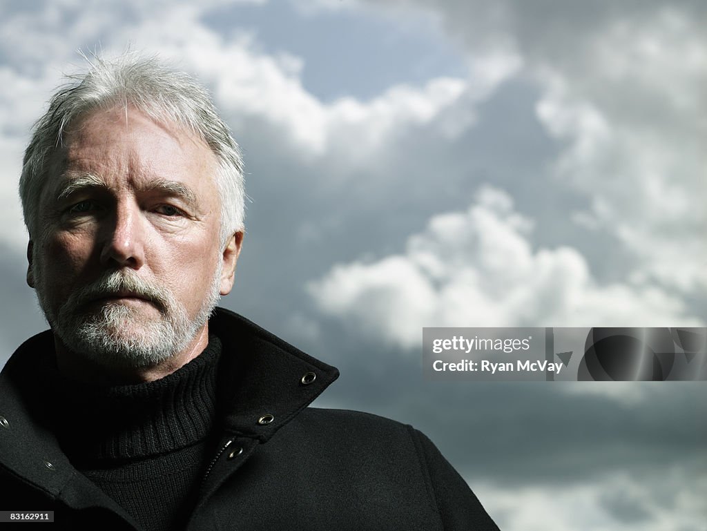 Portrait of mature man against stormy sky.