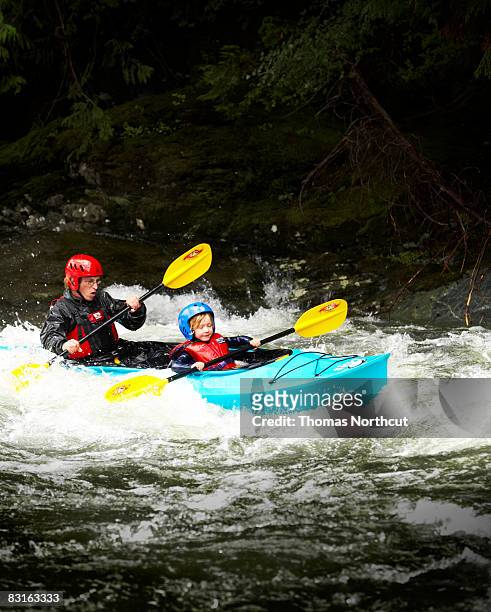 father and son kayaking through rapids. - white water kayaking stock pictures, royalty-free photos & images