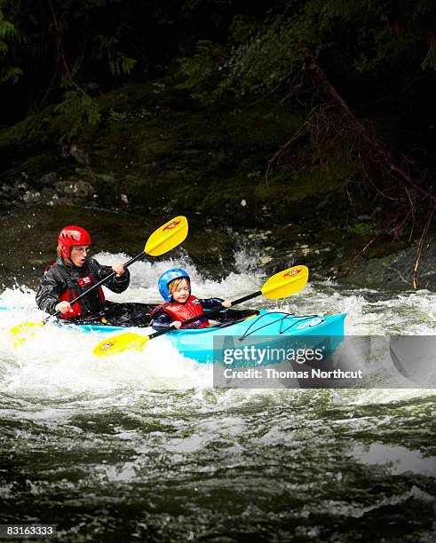 father and son kayaking through rapids. - kids kayaking stock pictures, royalty-free photos & images