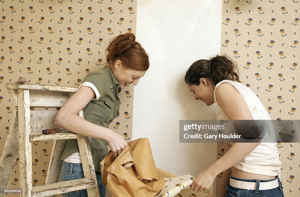 Friends removing one panel of wallpaper