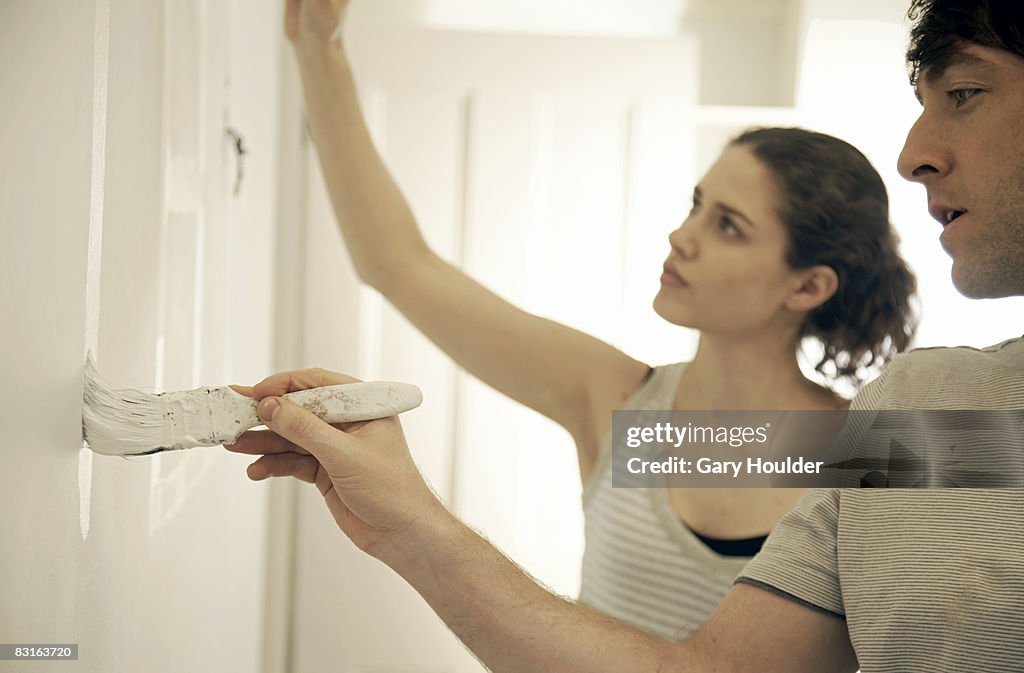 Couple painting on a house wall