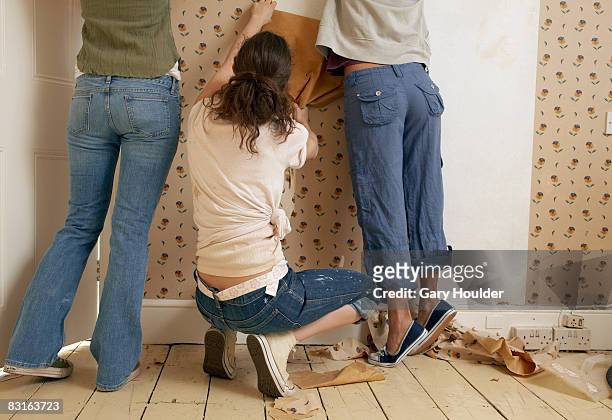 three friends tearing down wallpaper - vrouw behangen stockfoto's en -beelden
