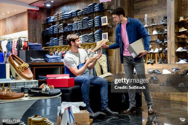 young man buying new shoes - shoe seller imagens e fotografias de stock