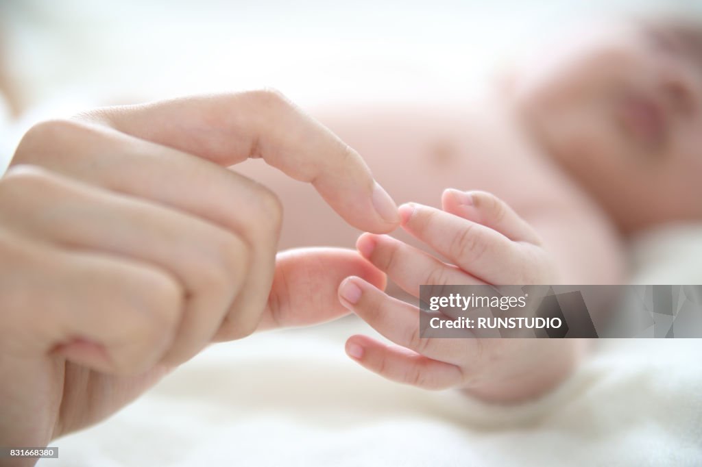 Mother touching baby's hand