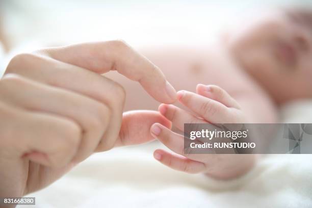 mother touching baby's hand - baby close up bed stock pictures, royalty-free photos & images