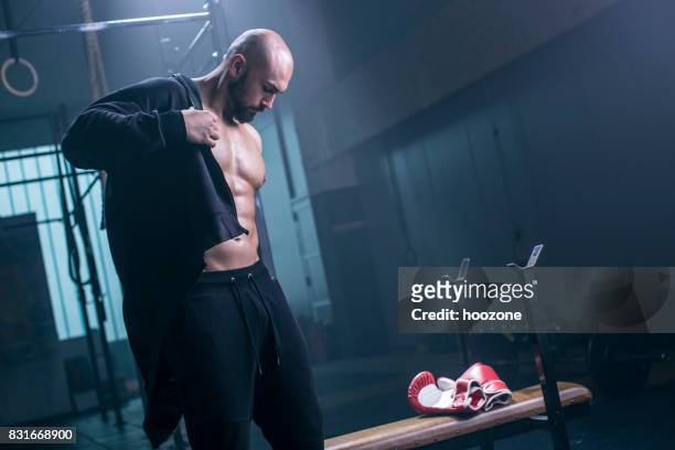 bodybuilder taking of hoodie in a gym - jacket stock pictures, royalty-free photos & images