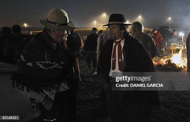 Two farmers talk near a bonfire in the side of the route 191, in the province of Buenos Aires on October 7 during a vigil in the fifth day of a...