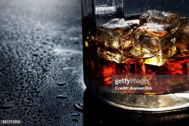 selective focus pure whisky with ice cube inside whisky glass on wet background - brandy stock pictures, royalty-free photos & images