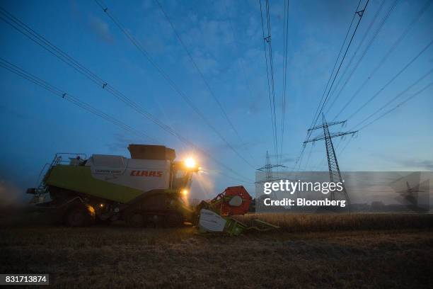 Claas KGaA Lexion 600 combine harvester operates in a wheat field below electricity cables in Wustermark, Germany, on Monday, Aug. 14, 2017. In...