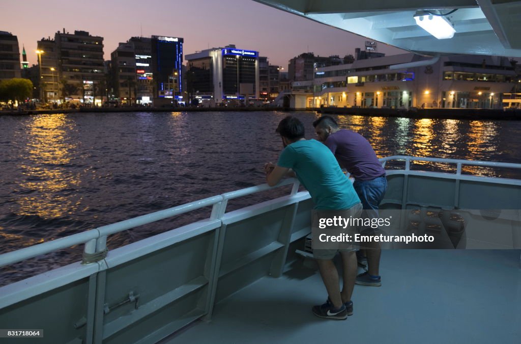 Passengers standing and chatting at the deck of passenger ferry at sunset in Izmir.