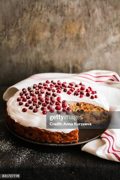 homemade christmas cake with dried fruits decorated with sweet vanilla meringue, fresh cranberry and icing sugar on a plate, selective focus - christmas cake stock pictures, royalty-free photos & images