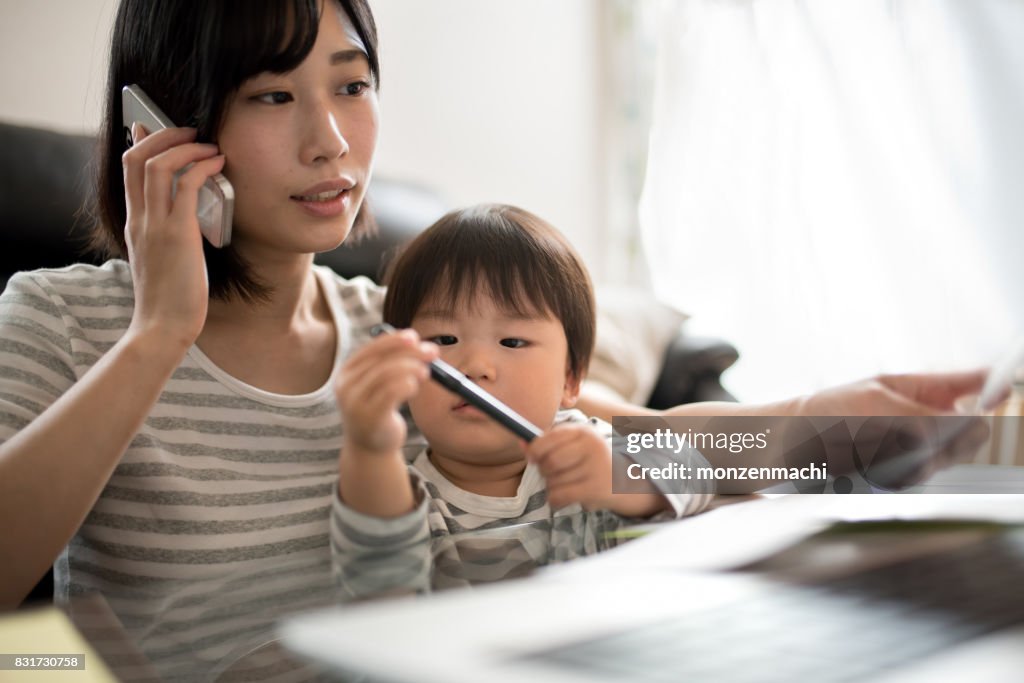 Young mother working in house with her child