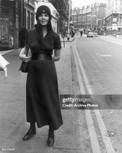 American actress Ali MacGraw stands on a street corner, wearing a dark dress and a knitted hat, London, England, 8th March 1971.