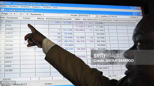 Man points at exchange rates posted on a board at the Regional Bourse for French West Africa where members of the West African Economic and Monetary...
