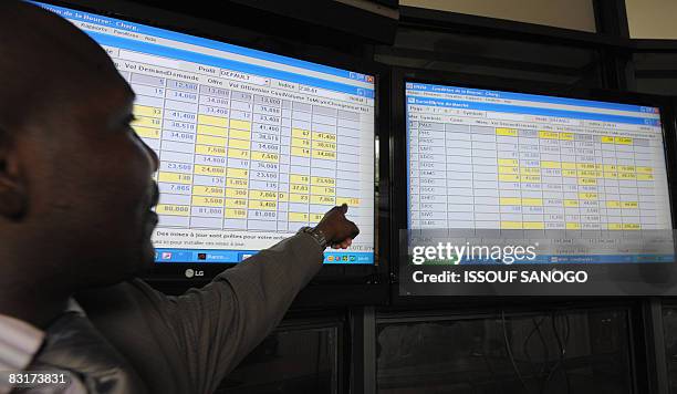 Man points at exchange rates posted on a board at the Regional Bourse for French West Africa where members of the West African Economic and Monetary...