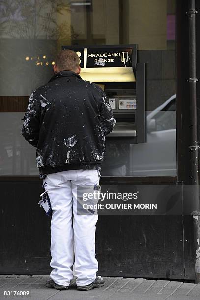 Man takes money from an automatic teller machine outside the Icelandic bank Kaupping on October 8, 2008 in Rejkjavik. The Icelandic state has...