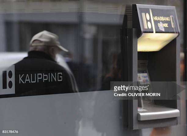 The shadow of a man is reflected on a window next to an automatic teller machine outside a branch of the Icelandic bank Kaupthing on October 8, 2008...