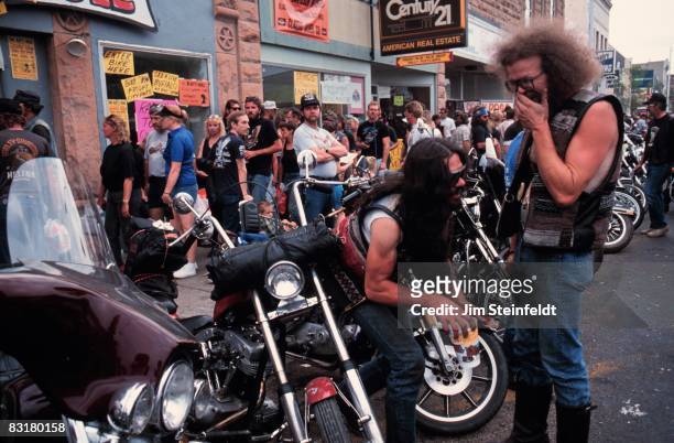 50th Anniversary of the World Famous Sturgis Motorcycle Rally. Laughing biker and his friend along a row of motorcycles in Sturgis, South Dakota on...