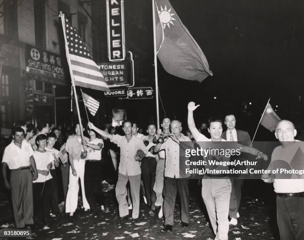 Crowd marches through NY's Chinatown to celebrate the end of World War II, V-J Day, in Chinatown; people are holding American and Chinese flags and...