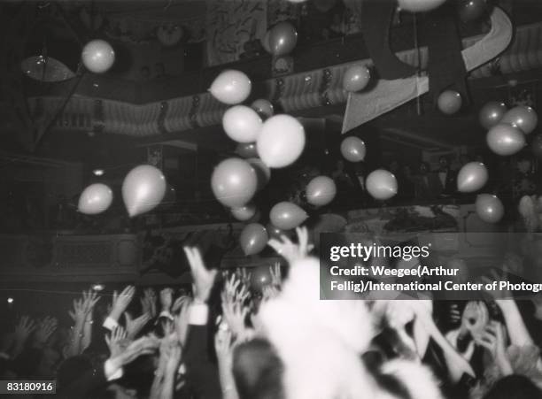 Ballons with prizes descend upon the outstretched hands of people at the Artists Equity Association's Artists Equity Ball , New York, 1954.