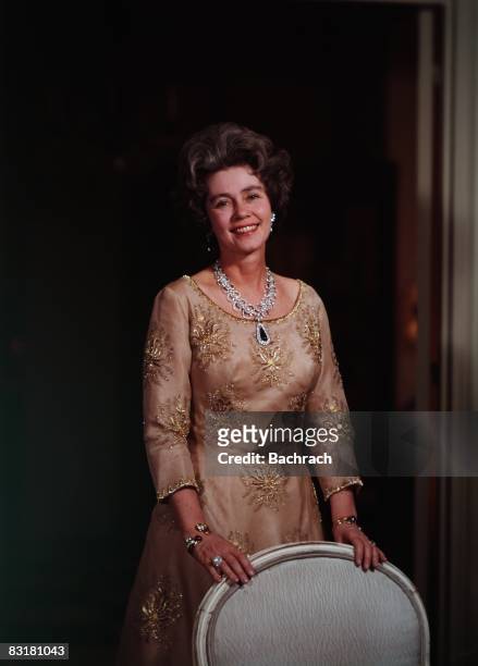 Standing portrait of the Dowager Queen of Greece, Queen Frederika of Hanover . She smiles while standing behind a chair, New York, 1961.