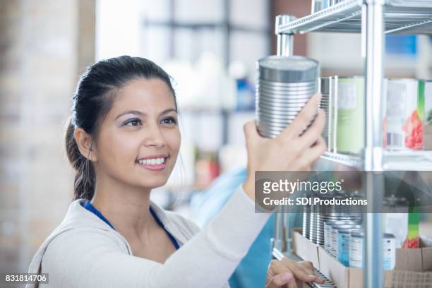 food bank volunteer checks expiration dates on canned goods - expiry date stock pictures, royalty-free photos & images